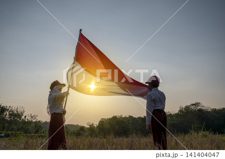 Two Indonesian school children in uniform proudly hold the red and white flag, symbolizing patriotism and national spirit. Hari Kemerdekaan, Merdeka, and Dirgahayu Indonesia on 17 Agustus Two Indonesian school children in uniform proudly hold the red and white flag, symbolizing patriotism and national spirit. Hari Kemerdekaan, Merdeka, and Dirgahayu Indonesia on 17 Agustus 141404047