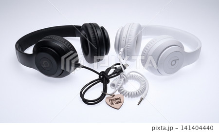 Black and white wireless headphones connected together with small heart tag headphones technology wireless listening connection electronic entertainment equipment minimalist accessory Black and white wireless headphones connected together with small heart tag headphones technology wireless listening connection electronic entertainment equipment minimalist accessory 141404440