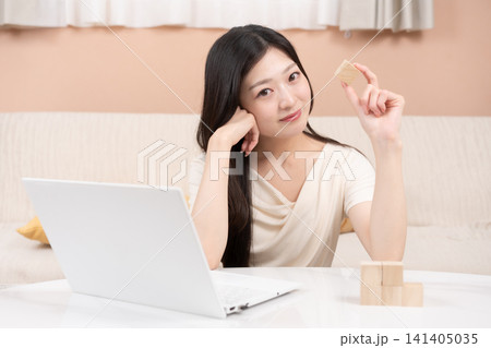 積立投資や資産形成をイメージする若い女性 ノートパソコンと積み木 積立投資や資産形成をイメージする若い女性 ノートパソコンと積み木 141405035