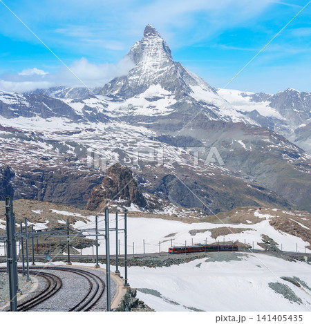 Iconic Matterhorn Mountain with Gornergrat Railway Train in Zermatt, Switzerland, Snow Capped Alpine Peak under Blue Sky, Famous Swiss Alps Landmark landscape and popular European Travel Destination 141405435