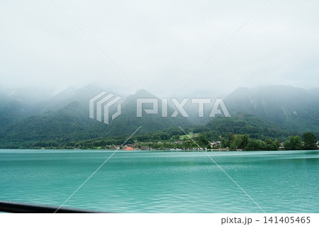 Scenic Cruise View of Lake Brienz from a Passenger Boat with Swiss Chalets Village, Alpine Mountains, Turquoise Lake and Mist, Switzerland. Picturesque Landscape and Famous Europe Travel Destination 141405465
