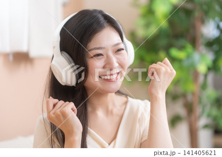 ワイヤレスヘッドフォンで音楽を楽しむ笑顔の若い女性 ワイヤレスヘッドフォンで音楽を楽しむ笑顔の若い女性 141405621
