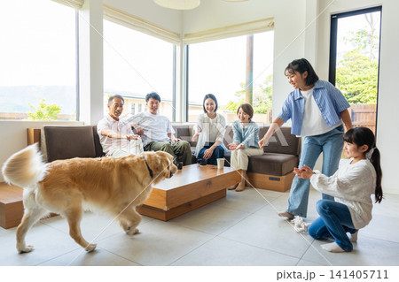 リビングで愛犬と触れ合う3世代の家族 リビングで愛犬と触れ合う3世代の家族 141405711