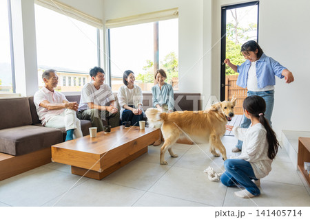 リビングで愛犬と触れ合う3世代の家族 リビングで愛犬と触れ合う3世代の家族 141405714