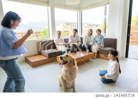 リビングで愛犬と触れ合う3世代の家族 リビングで愛犬と触れ合う3世代の家族 141405719