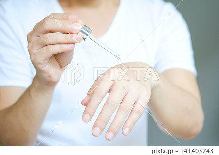 Young man's hand He drops the Collagen Moisturizer serum on his hands, and Protector skin Treatment facial essence oil, Vitamin C. Beauty and spa Concept. Young man's hand He drops the Collagen Moisturizer serum on his hands, and Protector skin Treatment facial essence oil, Vitamin C. Beauty and spa Concept. 141405743