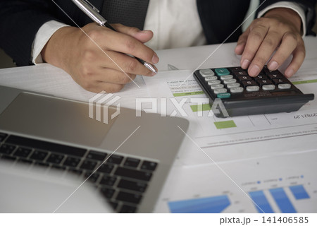 businessman or accountant calculating taxes on calculator and analyzing financial graph data document with laptop. Corporate finance, budget planning and accounting report concept. businessman or accountant calculating taxes on calculator and analyzing financial graph data document with laptop. Corporate finance, budget planning and accounting report concept. 141406585