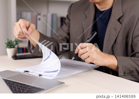 businessman checking GPA calculator document and academic report for career planning and education assessment. Male hand holding pen with laptop on desk for business data analysis. businessman checking GPA calculator document and academic report for career planning and education assessment. Male hand holding pen with laptop on desk for business data analysis. 141406589
