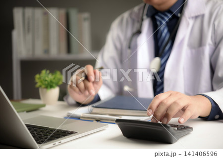 doctor using calculator and laptop for medical cost calculation, health insurance billing, and hospital budget management in clinic office. High quality healthcare financial concept. doctor using calculator and laptop for medical cost calculation, health insurance billing, and hospital budget management in clinic office. High quality healthcare financial concept. 141406596