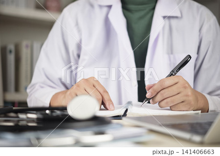 Male doctor or medical student hand writing notes in notebook with stethoscope and laptop on desk. Concept of medical education, clinical research, and continuous healthcare learning. Male doctor or medical student hand writing notes in notebook with stethoscope and laptop on desk. Concept of medical education, clinical research, and continuous healthcare learning. 141406663