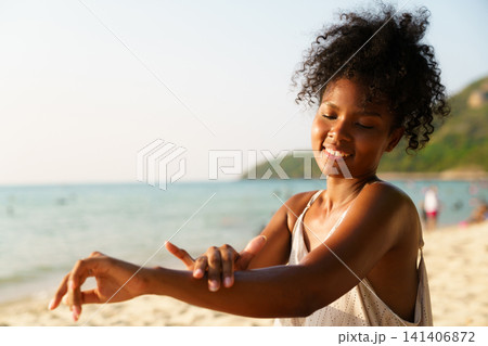 Black woman applying sunscreen or sunblock lotion on the beach Black woman applying sunscreen or sunblock lotion on the beach 141406872