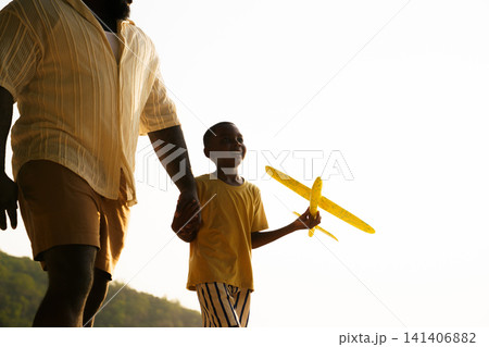 Black father and son playing with toy airplane on the beach Black father and son playing with toy airplane on the beach 141406882