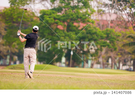 Male golfer finishing his swing on a lush green golf course Male golfer finishing his swing on a lush green golf course 141407086