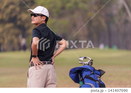 Male golfer holding his lower back in pain on the golf course Male golfer holding his lower back in pain on the golf course 141407090