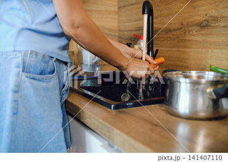 Person washing carrots in kitchen sink during daytime Person washing carrots in kitchen sink during daytime 141407110