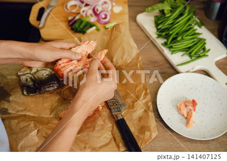 Top view of hands tearing hot smoked pink salmon into pieces Top view of hands tearing hot smoked pink salmon into pieces 141407125