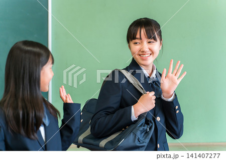 学校の教室で友達に挨拶する,登校する笑顔の中学生,高校生の女の子 学校の教室で友達に挨拶する,登校する笑顔の中学生,高校生の女の子 141407277