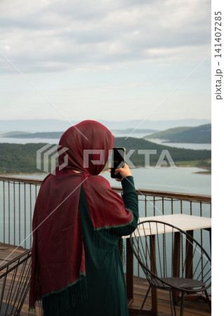 Muslim Woman Wearing Hijab Overlooking Scenic Island Landscape In Turkey Muslim Woman Wearing Hijab Overlooking Scenic Island Landscape In Turkey 141407285