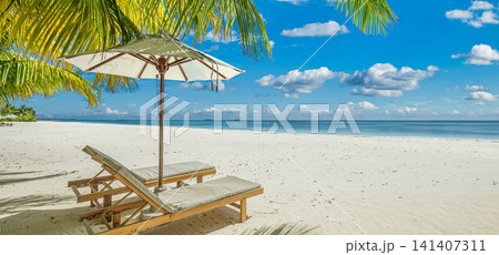 Picturesque tropical beach wooden deck chairs sun umbrella under palm fronds white sand turquoise sea blue sky. Perfect summer vacation travel landscape resort paradise. Luxury getaway relax scenic Picturesque tropical beach wooden deck chairs sun umbrella under palm fronds white sand turquoise sea blue sky. Perfect summer vacation travel landscape resort paradise. Luxury getaway relax scenic 141407311