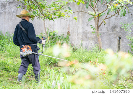 初夏に草刈り機で草刈りをする高齢男性 141407590