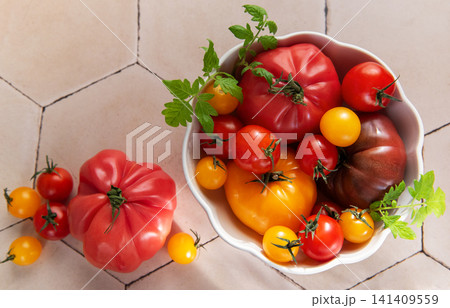 Fresh heirloom tomatoes in bowl on tile surface Fresh heirloom tomatoes in bowl on tile surface 141409559