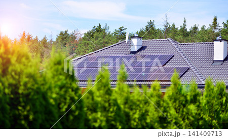 A single-family house with solar panels on a sunny day amidst green surroundings. Solar panels on roof of residential home providing ecofriendly green energy generation. A single-family house with solar panels on a sunny day amidst green surroundings. Solar panels on roof of residential home providing ecofriendly green energy generation. 141409713