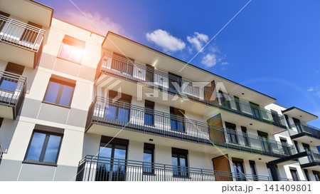 Contemporary urban apartment block with protruding balconies, white and grey facade contrast and reflective windows under a bright sky. Contemporary urban apartment block with protruding balconies, white and grey facade contrast and reflective windows under a bright sky. 141409801