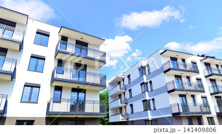Contemporary urban apartment block with protruding balconies, white and grey facade contrast and reflective windows under a bright sky. Contemporary urban apartment block with protruding balconies, white and grey facade contrast and reflective windows under a bright sky. 141409806