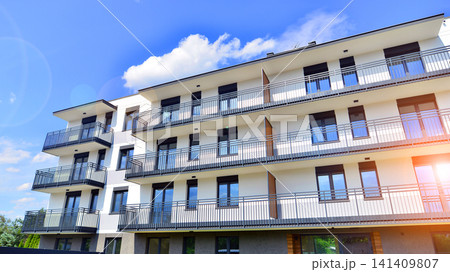 Contemporary urban apartment block with protruding balconies, white and grey facade contrast and reflective windows under a bright sky. Contemporary urban apartment block with protruding balconies, white and grey facade contrast and reflective windows under a bright sky. 141409807