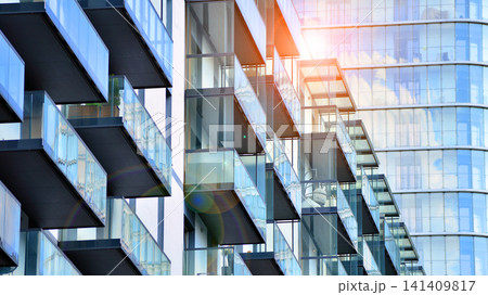 Contemporary urban apartment block with protruding balconies, white and grey facade contrast and reflective windows under a bright sky. 141409817