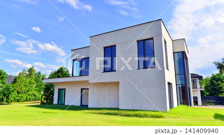 Modern rectangular minimalist house for familie. Exterior view of two story house with modern design and having black glass windows. Exterior view of modern style or houses for living. Modern rectangular minimalist house for familie. Exterior view of two story house with modern design and having black glass windows. Exterior view of modern style or houses for living. 141409940