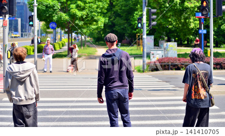 Warsaw, Poland. 20 May 2026. Street of a big city in summer time with residents, tourists and modern buildings. People of different ages crossing the road through. Warsaw, Poland. 20 May 2026. Street of a big city in summer time with residents, tourists and modern buildings. People of different ages crossing the road through. 141410705