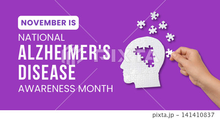 Alzheimer's awareness. Hand places puzzle piece onto brain graphic against purple background Alzheimer's awareness. Hand places puzzle piece onto brain graphic against purple background 141410837