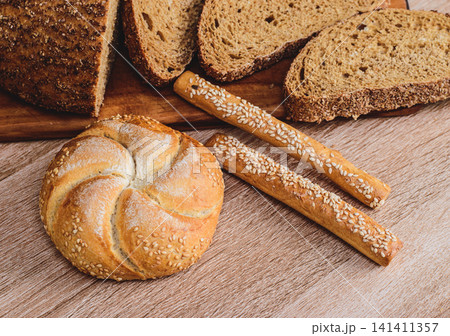 French baguettes. Fresh crispbread. Bread background. Different breed on wooden background. French baguettes. Fresh crispbread. Bread background. Different breed on wooden background. 141411357