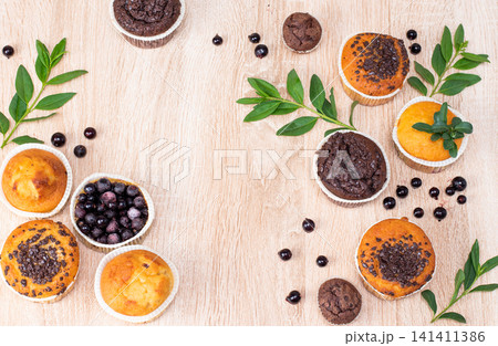 Chocolate muffin and nut muffin, homemade bakery on dark background. Muffin with blueberries on a wooden table. Fresh berries and sweet pastries on the board. Chocolate muffin and nut muffin, homemade bakery on dark background. Muffin with blueberries on a wooden table. Fresh berries and sweet pastries on the board. 141411386