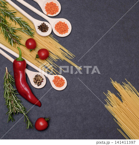 Italian food ingredients.Still life of cooking pasta on a black background top view. Wooden spoons with spices. Frame of products and vegetables. Italian food ingredients.Still life of cooking pasta on a black background top view. Wooden spoons with spices. Frame of products and vegetables. 141411397