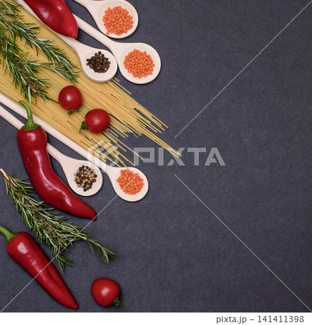 Italian food ingredients.Still life of cooking pasta on a black background top view. Wooden spoons with spices. Frame of products and vegetables. Italian food ingredients.Still life of cooking pasta on a black background top view. Wooden spoons with spices. Frame of products and vegetables. 141411398