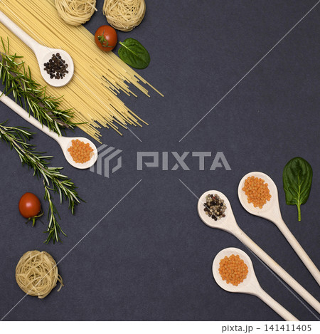 Italian food ingredients.Still life of cooking pasta on a black background top view. Wooden spoons with spices. Frame of products and vegetables. 141411405