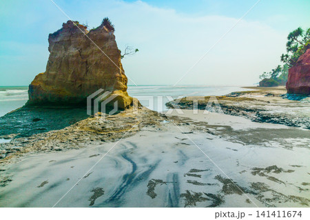 Aerial view of coastal rock formations rising from the sea with crashing waves and sandy beach in Indonesia Aerial view of coastal rock formations rising from the sea with crashing waves and sandy beach in Indonesia 141411674