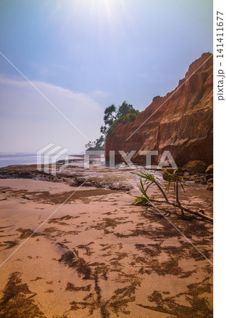 Aerial view of coastal rock formations rising from the sea with crashing waves and sandy beach in Indonesia 141411677