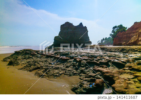 Aerial view of coastal rock formations rising from the sea with crashing waves and sandy beach in Indonesia Aerial view of coastal rock formations rising from the sea with crashing waves and sandy beach in Indonesia 141411687