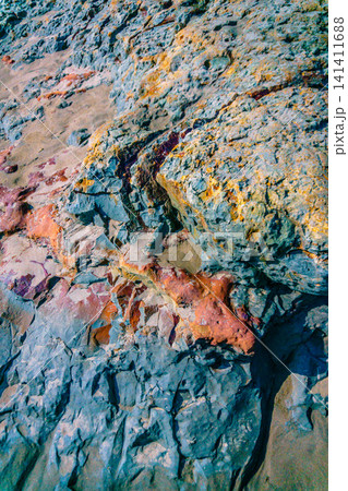 Aerial view of coastal rock formations rising from the sea with crashing waves and sandy beach in Indonesia 141411688