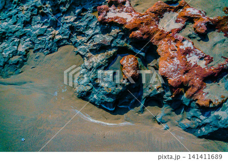 Aerial view of coastal rock formations rising from the sea with crashing waves and sandy beach in Indonesia Aerial view of coastal rock formations rising from the sea with crashing waves and sandy beach in Indonesia 141411689