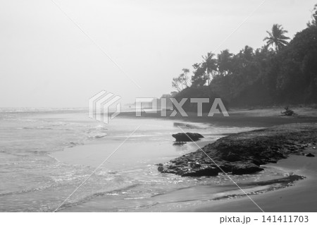 Aerial view of coastal rock formations rising from the sea with crashing waves and sandy beach in Indonesia 141411703