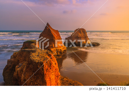 Aerial view of coastal rock formations rising from the sea with crashing waves and sandy beach in Indonesia Aerial view of coastal rock formations rising from the sea with crashing waves and sandy beach in Indonesia 141411710