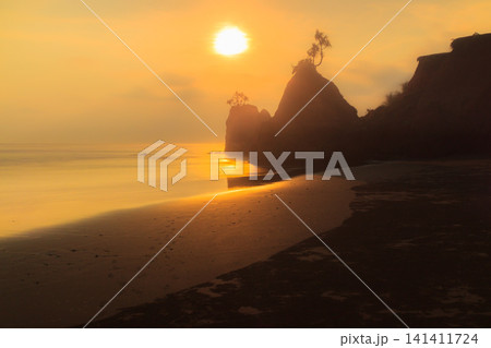 Aerial view of coastal rock formations rising from the sea with crashing waves and sandy beach in Indonesia 141411724