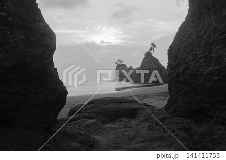 Aerial view of coastal rock formations rising from the sea with crashing waves and sandy beach in Indonesia 141411733