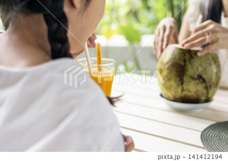 girl drinking fresh mango juice smoothie at outdoor tropical garden cafe in bali 141412194