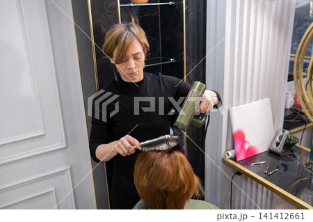Young female hairdresser styling a haircut with a styler. in beauty salon Stock Photo 141412661