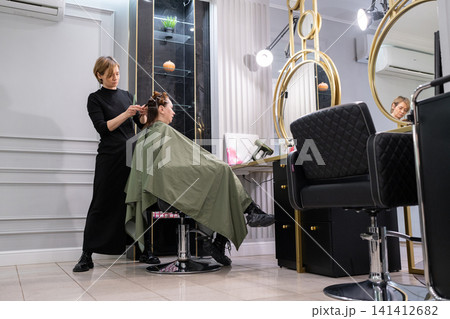 Young female hairdresser stylist working with scissors in beauty salon Stock Photo 141412682